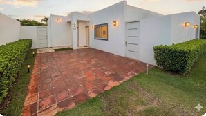 A modern building with a paved courtyard, white walls, and a number '30' sign. - Cozy 2BR Villa in Ocean Village (Sosúa)