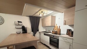 Eine moderne Küche mit einem Holztisch, einer Kaffeemaschine, einem Wasserkocher und einem Herd.