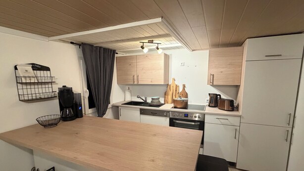 Eine moderne Küche mit Holzausstattung, einem Backofen, einer Spüle und einer Kaffeemaschine.