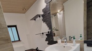 Ein modernes Badezimmer mit einem großen Waschbecken, einem Spiegel und Holzboden.