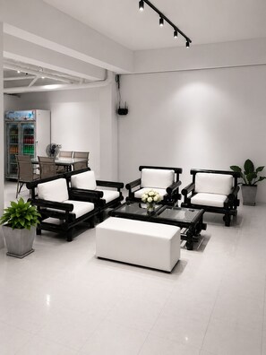 A modern living room with a sofa set, a coffee table, and a fan. There is a refrigerator with beverages and a potted plant. - Holiday House Kata & Karon Phuket (Karon)