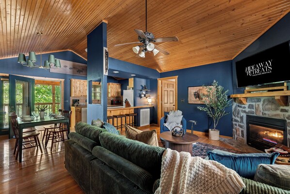 A spacious living area with a large sofa, a fireplace, and a television displaying 'Hideaway Retreats Vacation Rentals.'