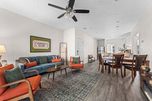 Ein modernes Wohnzimmer mit einer Couch, Sesseln, einem Couchtisch und einem Essbereich mit Stühlen und einem Tisch.