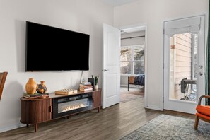 Ein Wohnzimmer mit Flachbildfernseher, Kamin, Bücherregal und einer Tür zu einem Außenbereich.