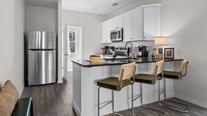 A modern kitchen with white cabinets, stainless steel appliances, and a central island with bar stools. - Pool Steps Away! Perfect for Families! Walk-in! (Branson)