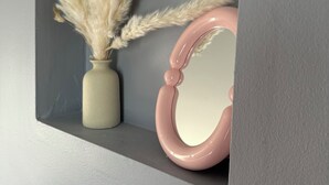 A shelf with a vase of pampas grass and a pink mirror. - Willow & Wildflower Retreat | Cozy, Unique, Family Stay (Edmonton)