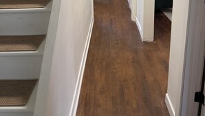 A staircase leading to a landing with a wooden floor, white walls, and a door on the right. - Willow & Wildflower Retreat | Cozy, Unique, Family Stay (Edmonton)