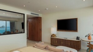 Moderni hotellihuone, jossa on suuri sänky, televisio, puinen vaatekaappi ja näkymä merelle.