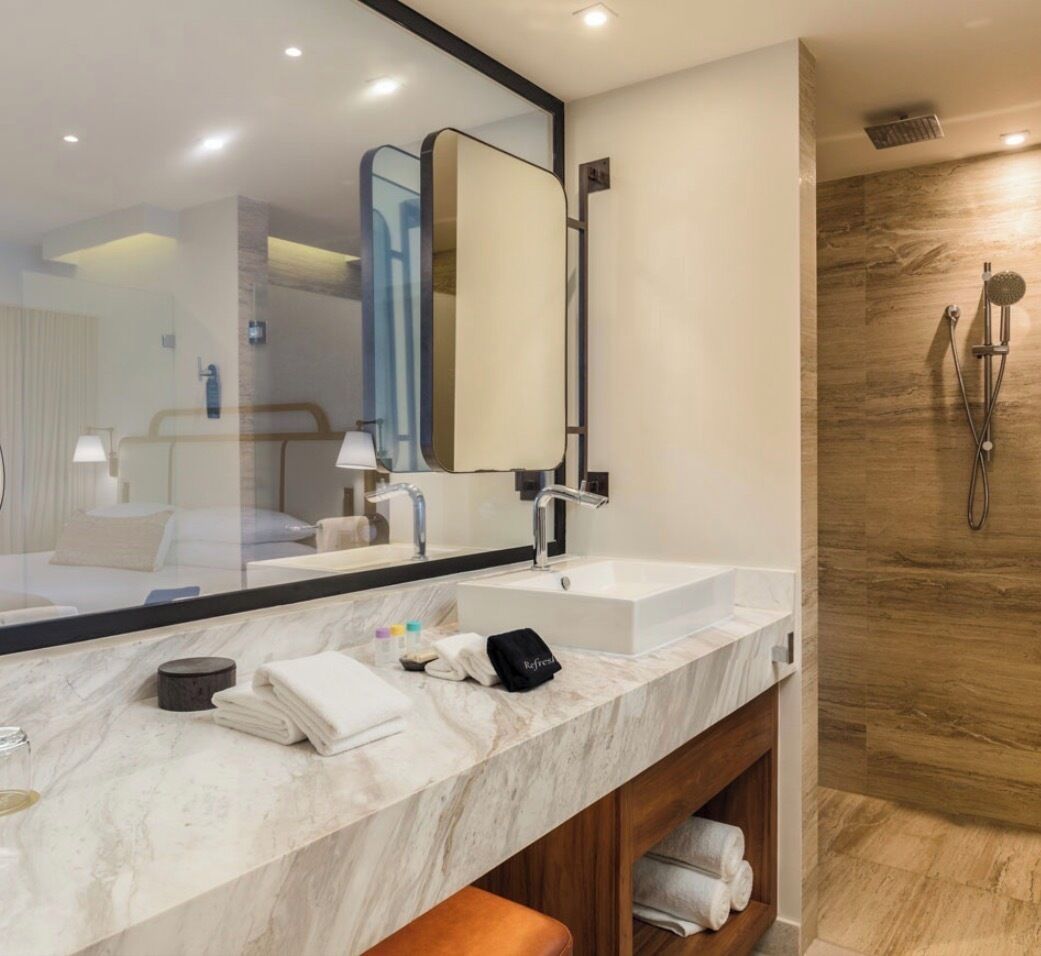 Une salle de bain moderne avec un grand miroir, un lavabo et un espace douche.
