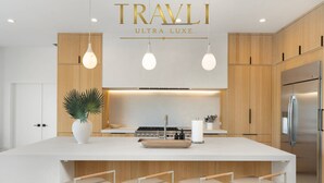 A modern kitchen with a central island, wooden cabinets, stainless steel appliances, and pendant lighting. - The Dreyfus | 5 Star Resort Style Designer Home (Scottsdale)