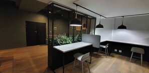 A modern office space with a wooden floor, a white desk, two chairs, a black partition, and pendant lighting. - 129 Comfortable 1-bedroom Apartment (Johannesburg)