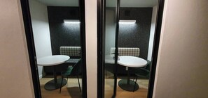 A room with a round table and two chairs, a checkered bench, and a wall-mounted light fixture. - 129 Comfortable 1-bedroom Apartment (Johannesburg)