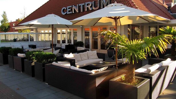 An outdoor seating area with wicker furniture and umbrellas at a hotel named CENTRUM. - Vacation home, Zeeland, Holland, North Sea, Starnd, WLAN, family-friendly park (Bruinisse)