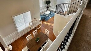 A spacious interior with a dining area, a staircase, and a view of the outdoors. - Modern and Stylish Retreat with Game Room (Tigard)