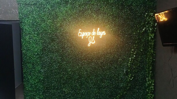 Une pièce avec un mur vert, un panneau lumineux au néon et une chaise blanche.