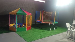 Un espace de jeux avec une piscine à balles et un ensemble de balançoires en filet.