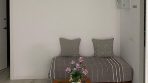 Una habitación pequeña con cama individual, una mesa de madera y una planta en maceta.