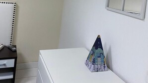Un dormitorio con una cama, un escritorio, una silla, un cuadro enmarcado y una ventana.