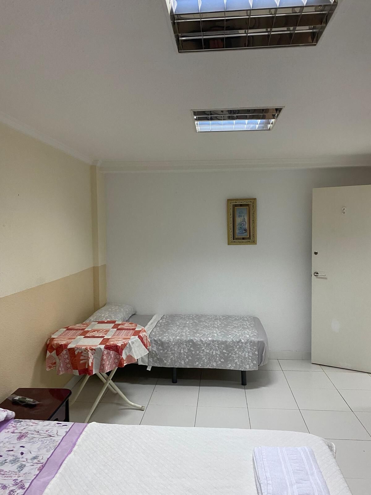A small, clean room with a bed, a table, and a door.