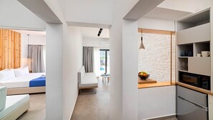 Et moderne hotelværelse med seng, et lille tekøkken, spiseplads og udsigt til det fri.