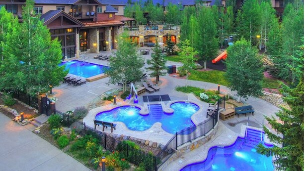 Ein Resort mit mehreren Schwimmbecken, Sitzgelegenheiten im Freien und einer Bergkulisse.