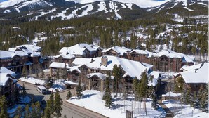 Eine schneebedeckte Lodge mit mehreren Gebäuden, umgeben von Bäumen und Bergen.
