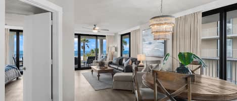 A spacious living area with a dining table, sofas, and a chandelier.