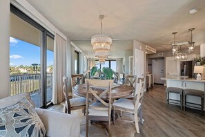 A spacious dining area with a round table and chairs, a chandelier, and a view of the outdoors. - Beachfront Corner Unit Condo | Pool | Sleeps 6 (Orange Beach)