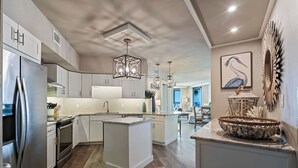 Een moderne keuken met een centraal eiland, roestvrijstalen apparatuur en een eethoek met uitzicht.