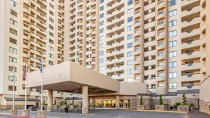 Un hôtel de grande hauteur avec une entrée centrale, de nombreux balcons et un mât pour drapeau.