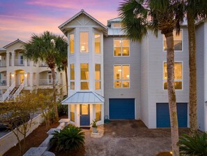 A multi-story building with a central tower, a covered patio, and a garage. - A Perfect Summer East (Walton County)