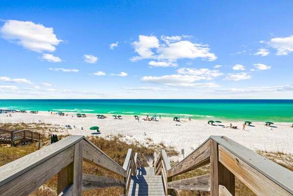A wooden staircase leading to a beach with clear turquoise water and a clear sky. - A Perfect Summer East (Walton County)