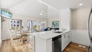 Een moderne keuken met witte kasten, een centraal eiland en een inbouw vaatwasser.