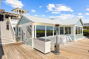 Ein modernes Gebäude mit Glasfassade, einer Holzterrasse und einer Treppe, die zu einer oberen Ebene führt.