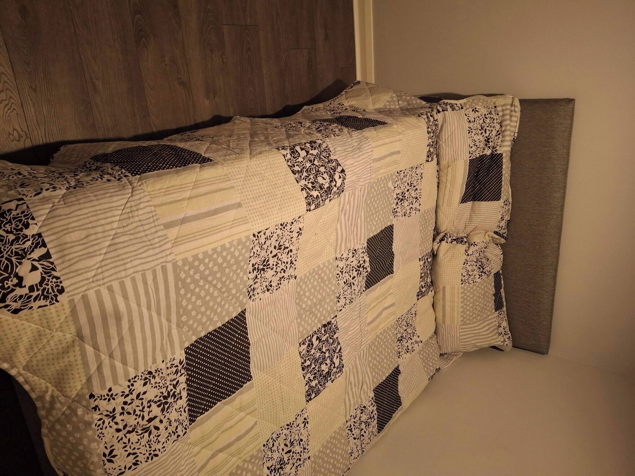 A bed with a quilt featuring geometric patterns and lace detailing.