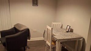 Ein Zimmer mit einem Bett, einem Sessel, einem Tisch und einer Pendelleuchte.