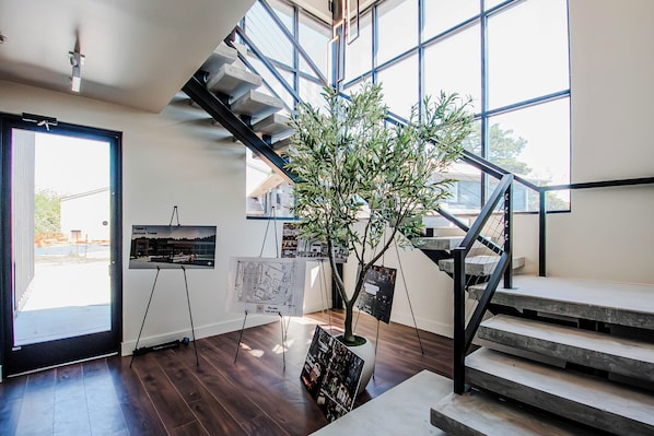 A staircase with a modern design, a potted plant, and architectural drawings on easels.