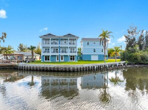 A waterfront property with a two-story building, a dock, and a grassy area. - Spacious Waterfront Home Near Downtown Tampa (Tampa)