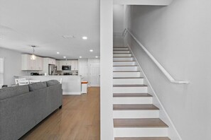 A modern kitchen with white cabinets, a central island, and a grey sofa. - Spacious Waterfront Home Near Downtown Tampa (Tampa)
