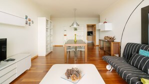 A modern living room with a dining table, sofa, TV, and a decorative pine cone centerpiece. - Ponta do Sol Apartment | Three-Bedroom (Ponta do Sol)