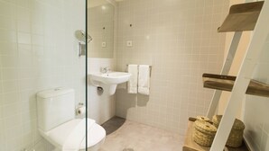 Et badeværelse med toilet, vask og bruseområde.