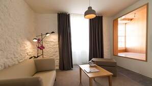 Een moderne kamer met een bank, een kleine tafel, een lamp en een raam met gordijnen.