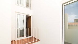 Een wit balkon met een metalen hekwerk, een raam en een deur.