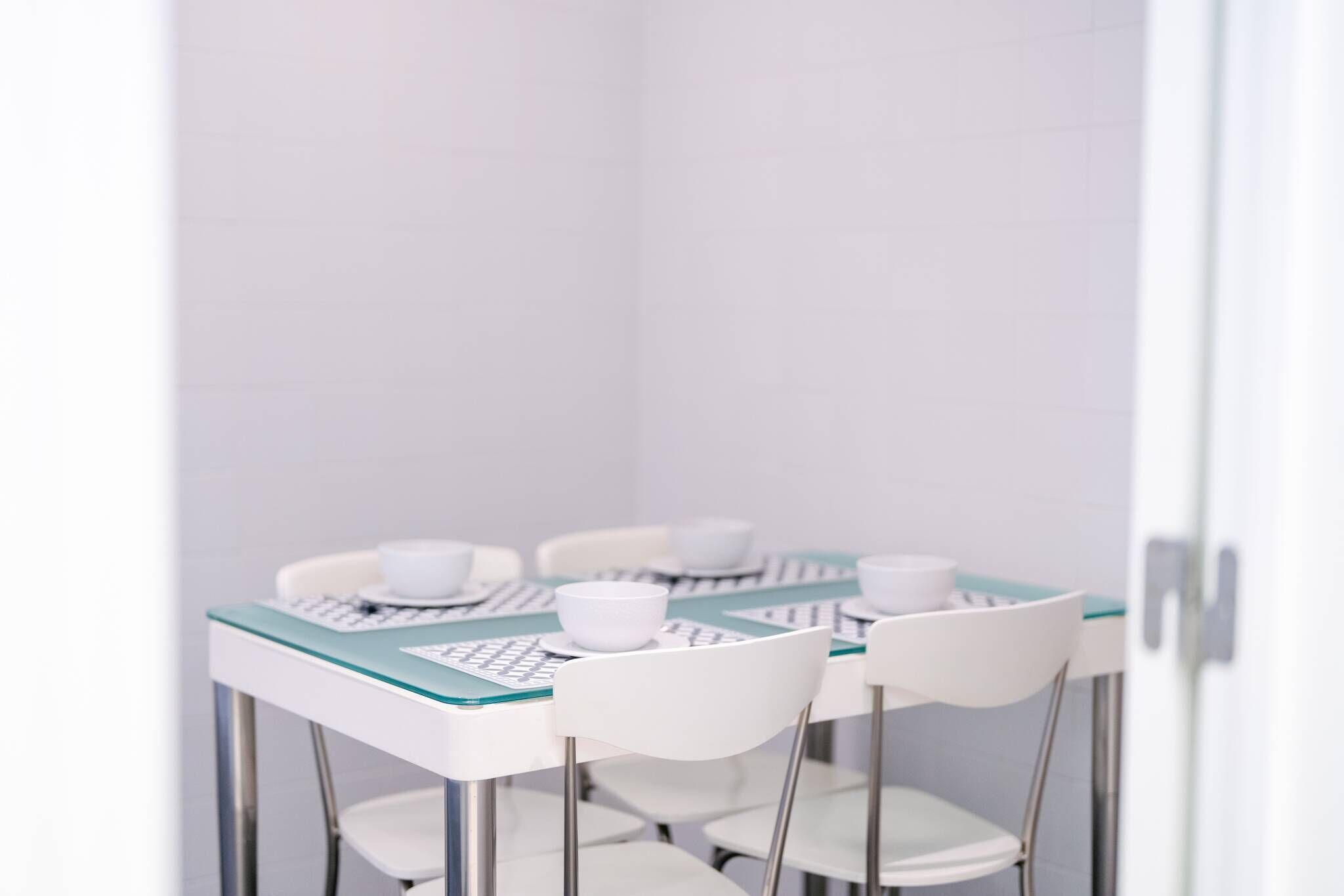 A modern, minimalist room with white furniture and a glass table.