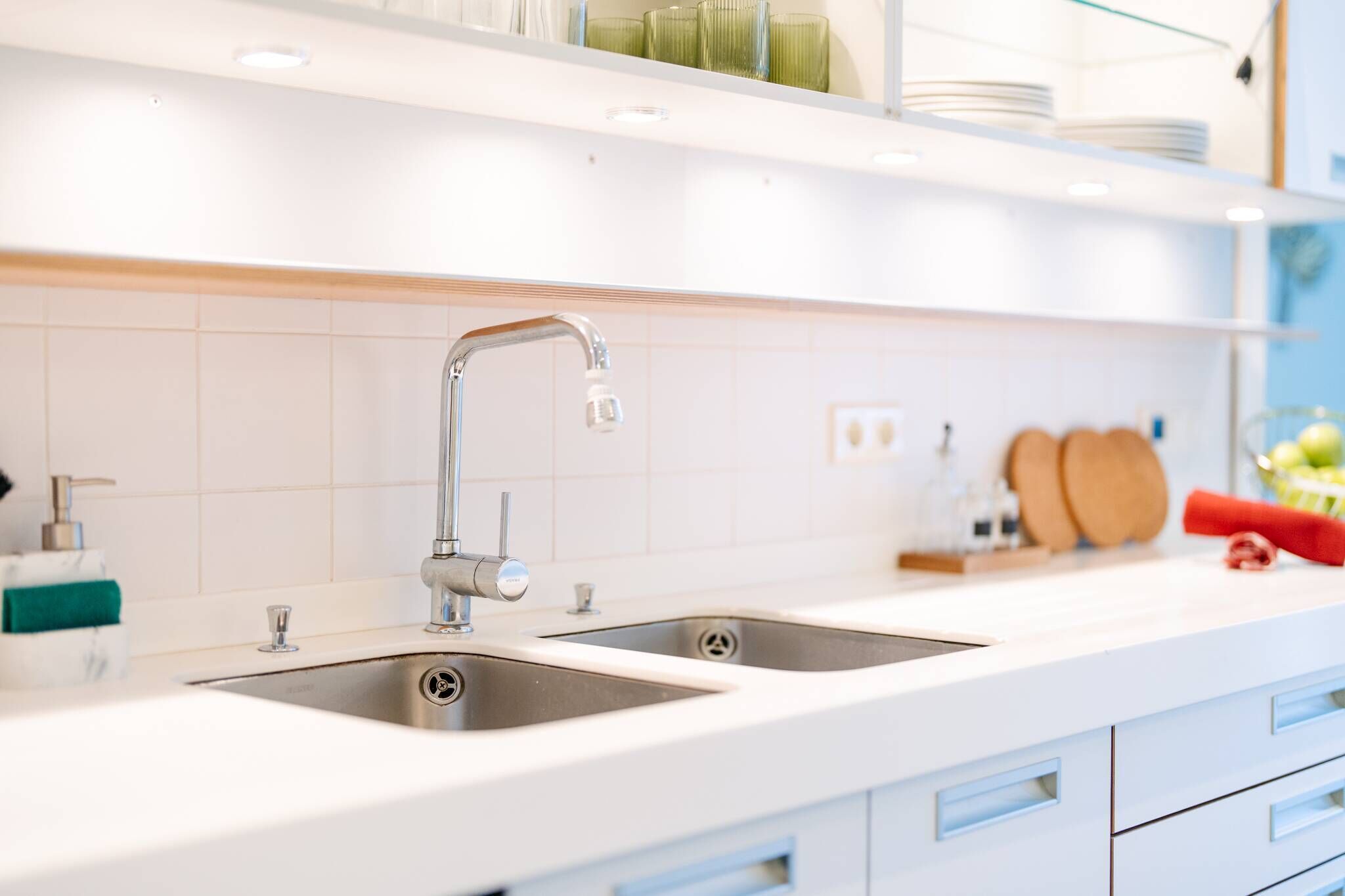 Een moderne keuken met twee spoelbakken, een kraan en een aanrecht met een zeepdispenser.