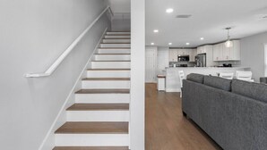 Ein modernes Interieur mit Treppe, Küche und Wohnbereich.