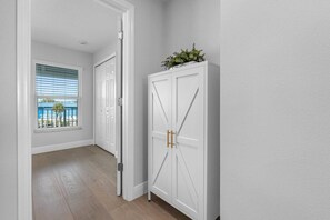A hallway with a white door, a window with blinds, and a view of a balcony with a railing. - Brand-New Waterfront Retreat Near Tampa Bay (Tampa)
