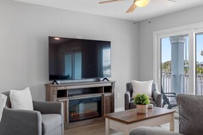 A living room with a flat-screen TV, fireplace, grey sofas, and a balcony with a view. - Brand-New Waterfront Retreat Near Tampa Bay (Tampa)