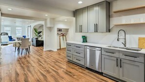 Una cocina moderna con gabinetes grises, lavavajillas de acero inoxidable y un lavabo con grifo.