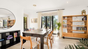 Ein moderner Essbereich mit Holztisch, Stühlen, einem Bücherregal und einem großen Fenster mit Blick auf Grünflächen.